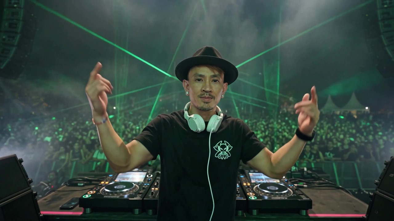 Jon Nguyen performing behind DJ decks with green stage lights